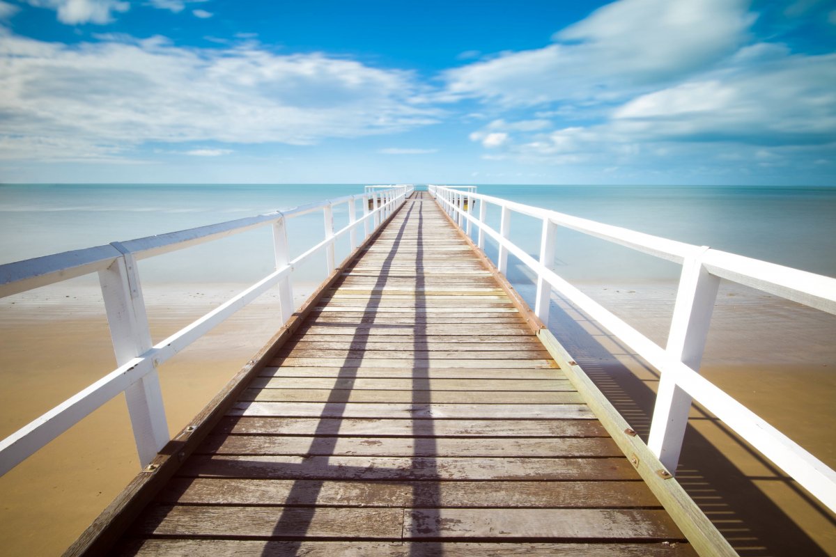Picture of wooden plank road with blue sky, white clouds and sea
