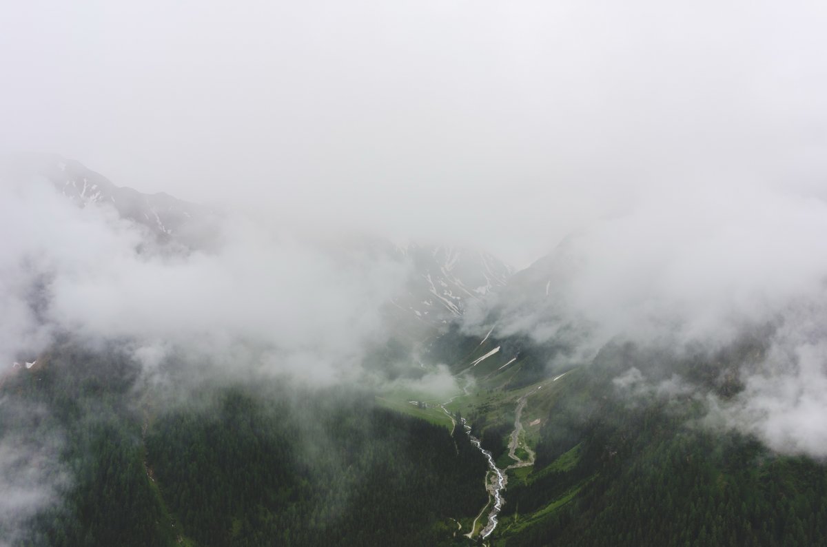 Overhead view of green mountain forest shrouded in clouds and mist